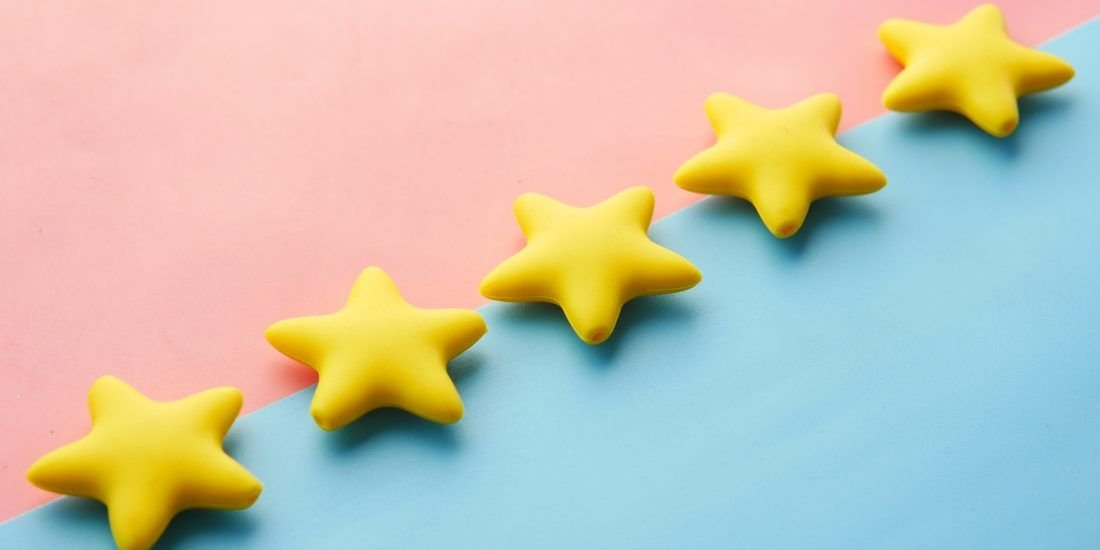 Five plastic stars lined up on a blue and pink background