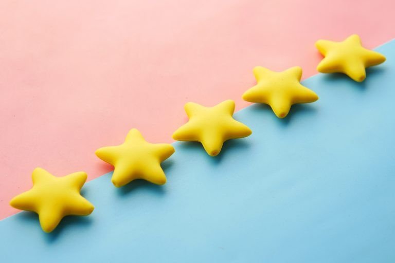 Five plastic stars lined up on a blue and pink background